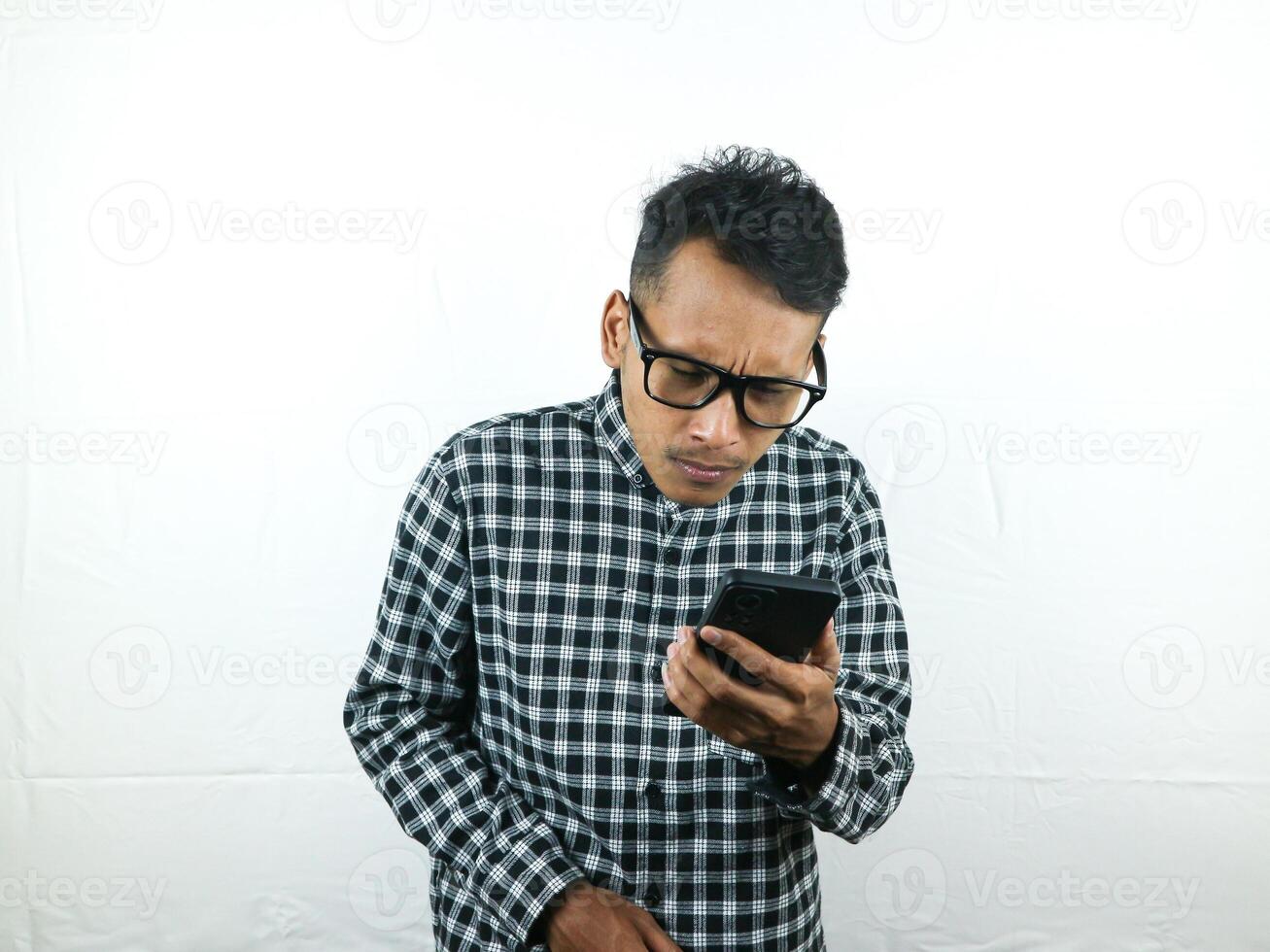 Portrait of asian man holding mobile phone reading, typing message with focus face expression. photo