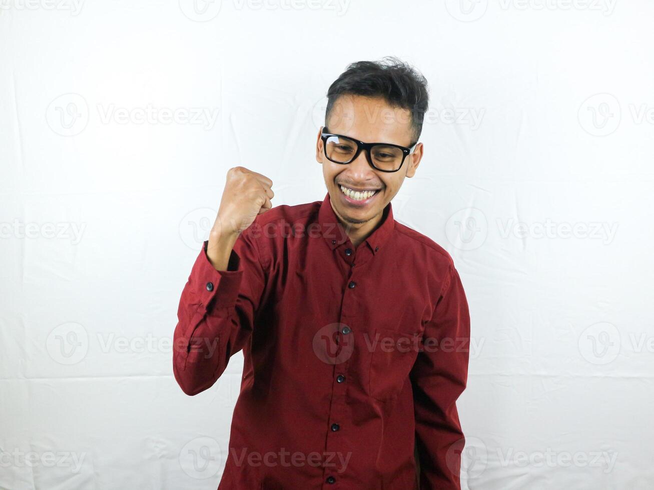 hermoso hombre en lentes celebrando éxito con apretando puño y contento cara expresión. foto