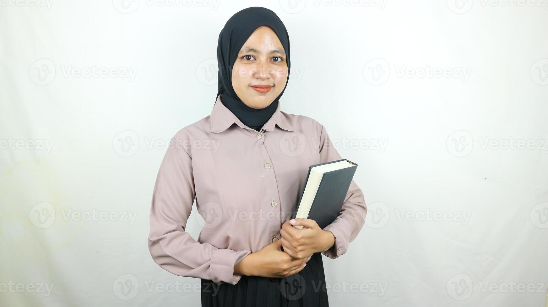 sonriente joven asiático musulmán estudiante participación libro, mirando a cámara aislado en blanco antecedentes. foto