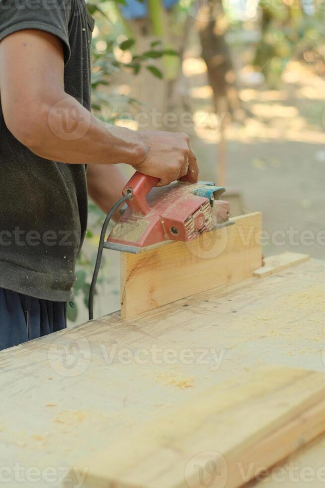 Close up of sanding a wood with orbital sander at workshop photo
