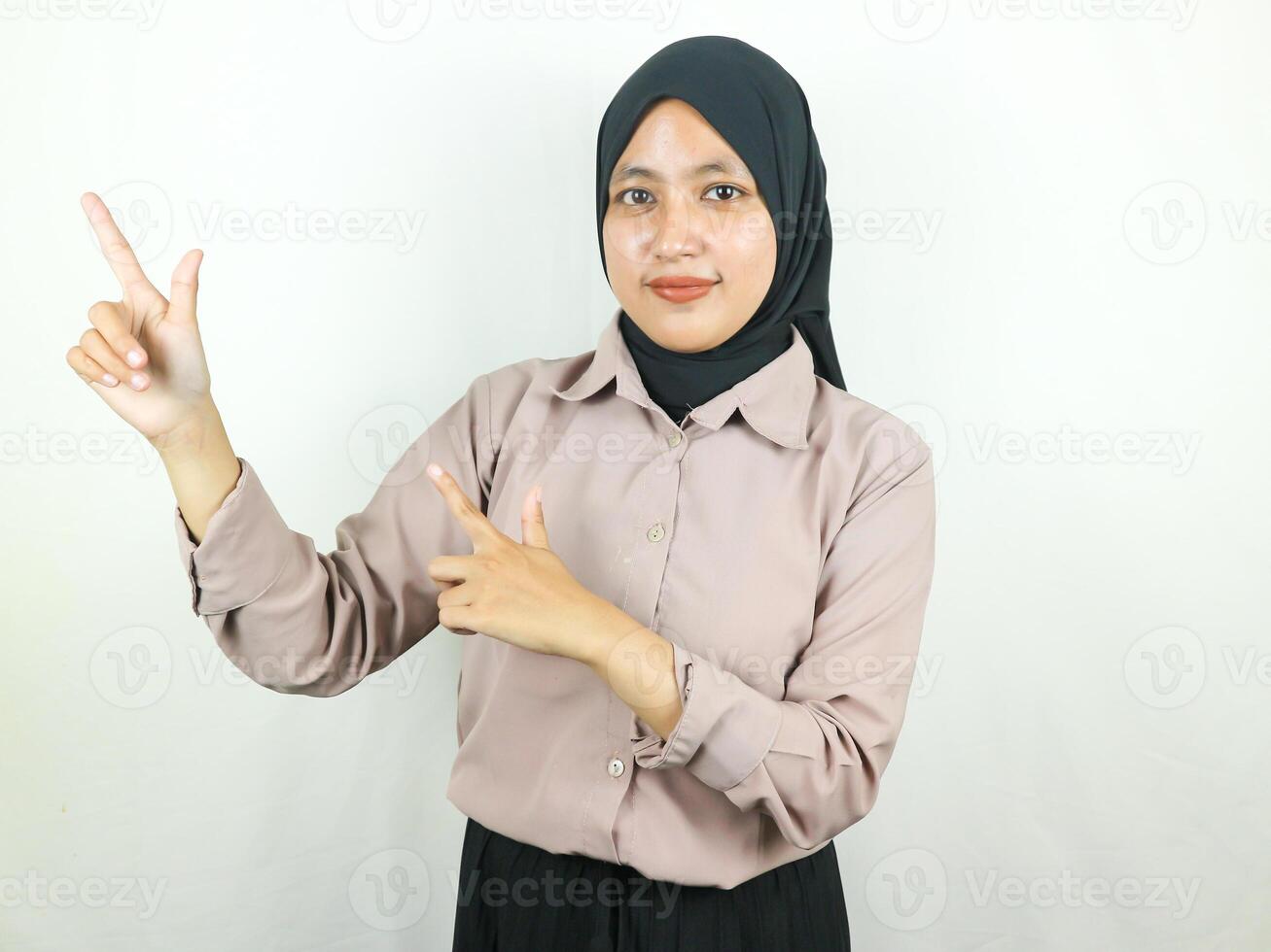 Beautiful Asian Muslim woman in hijab, smiling pointing fingers a side at copy space. photo