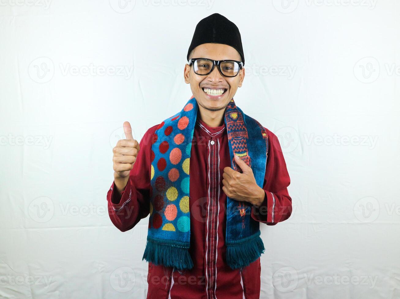 Moslem Asian man looking to the camera with happy face expression while waving hand to greet others photo