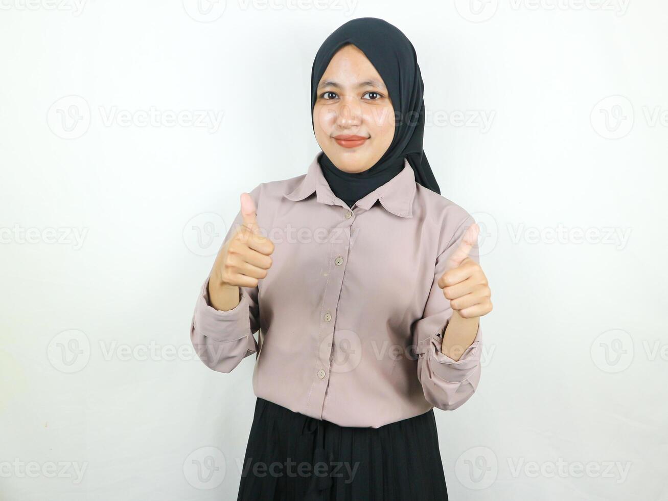 Smiling asian muslim woman in hijab showing thumb up in approval, recommending, like something good photo
