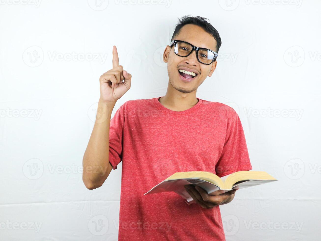 portrait of smiling asian man holding book and pointing finger up getting idea. photo