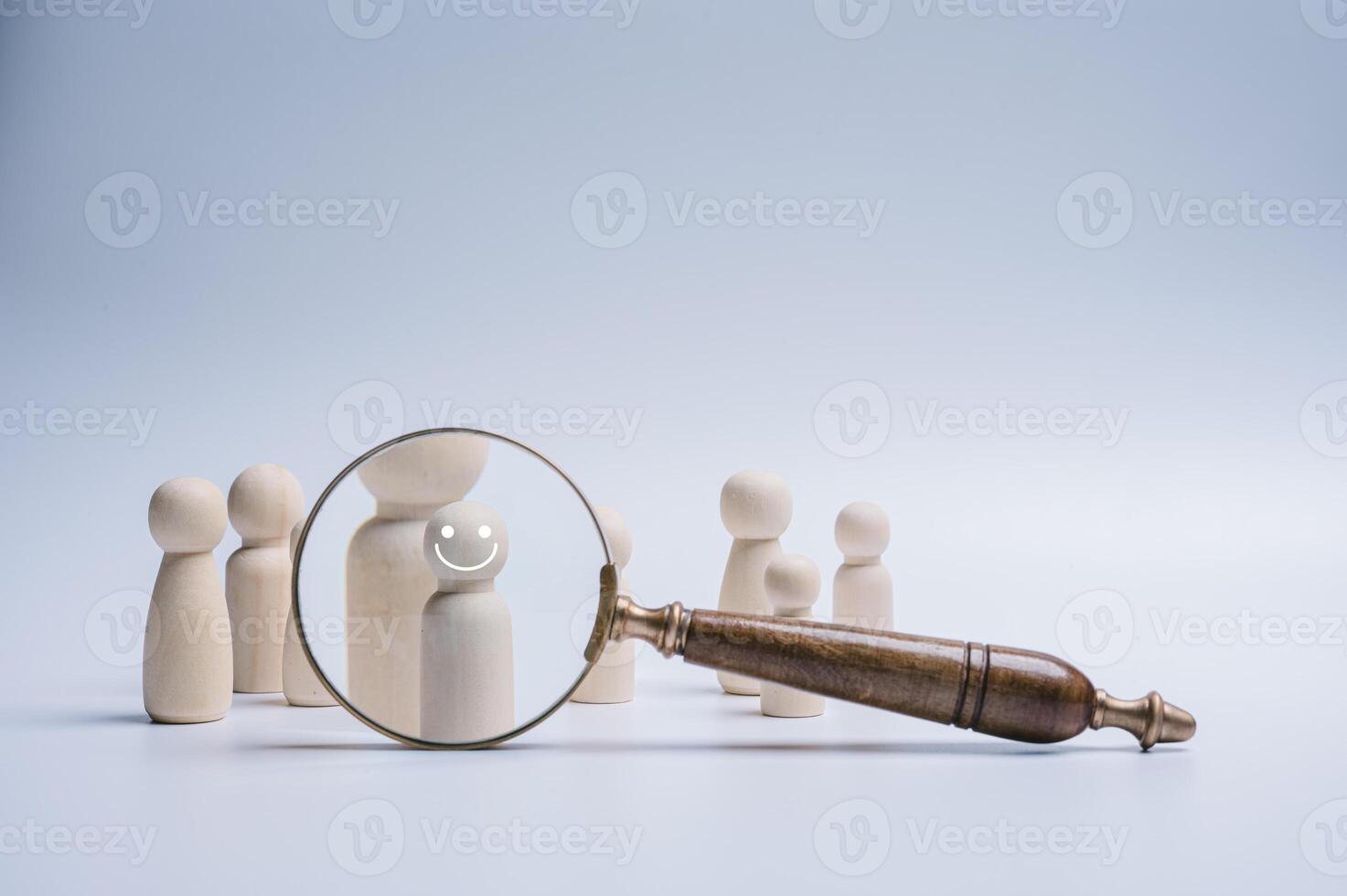 Magnifying glass focus wood doll which is among crowd for human development recruitment leadership and customer target group HRM or Human Resource Management concept photo