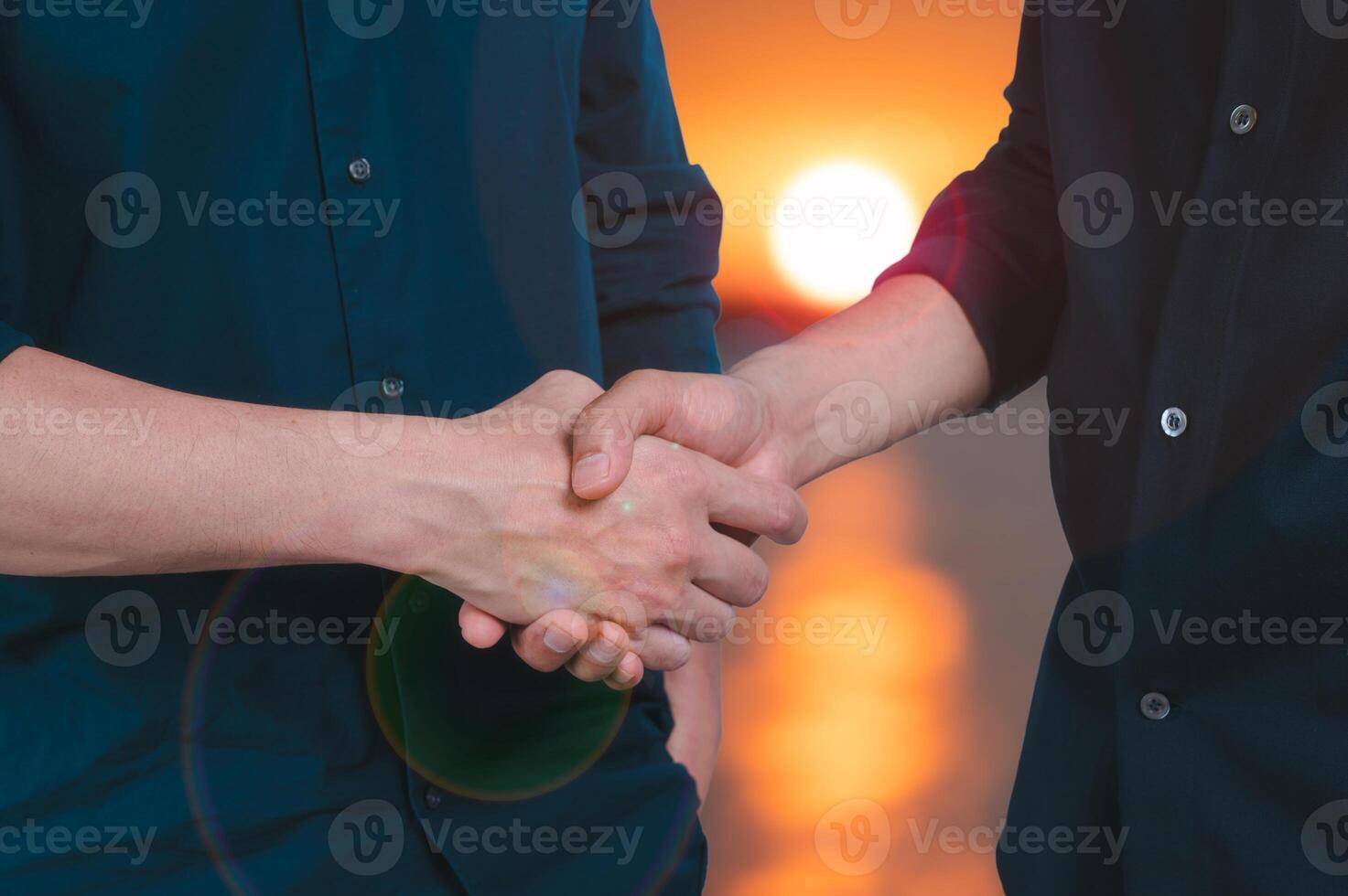 two men doing a handshake with blurred sunset background in concept of friendship partner and business dealing photo