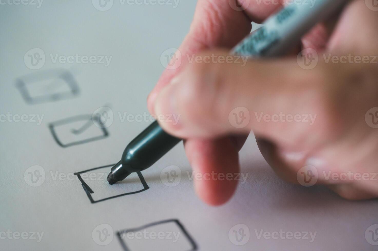 close up and selective focus hand using pen to making tick mark on check list box check list and marker photo