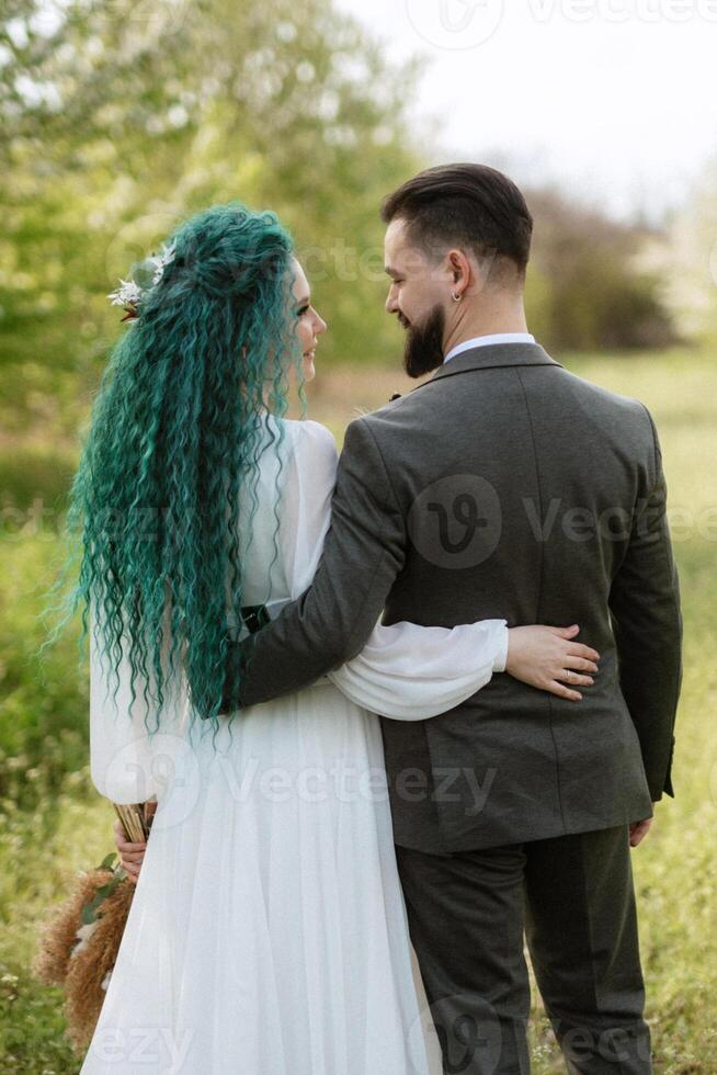 a bearded groom and a girl with green hair are walking photo