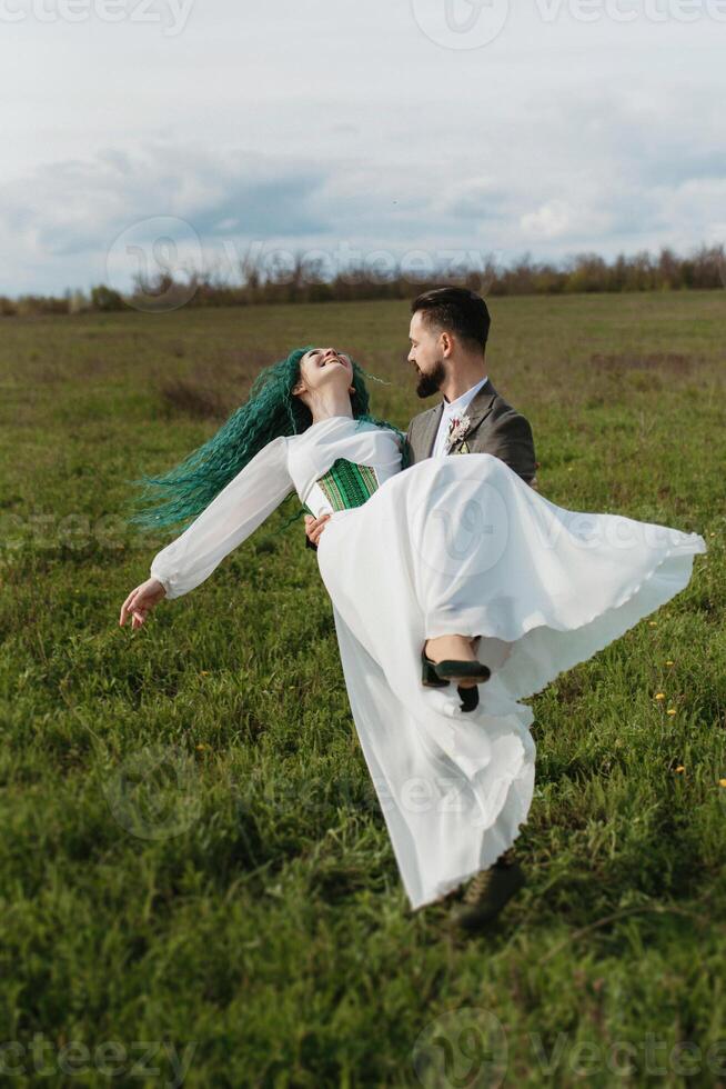 a bearded groom and a girl with green hair dance and twirl photo