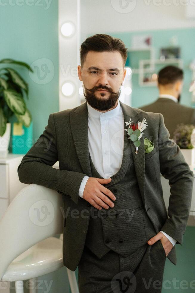 portrait of smiling groom with beard in gray color suit photo