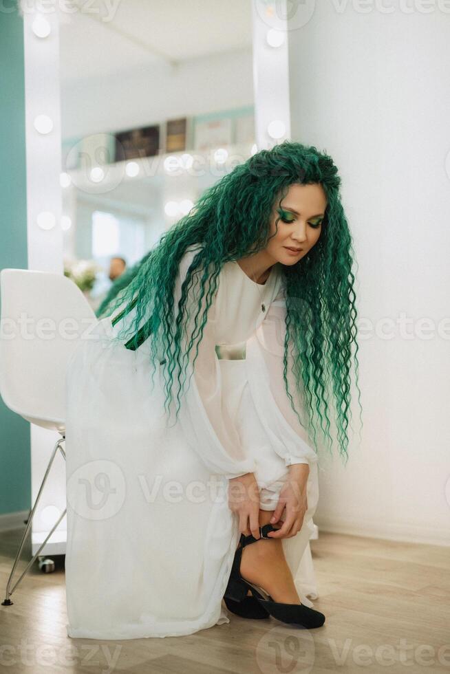 portrait of a bride with green curly hair in the beauty room photo