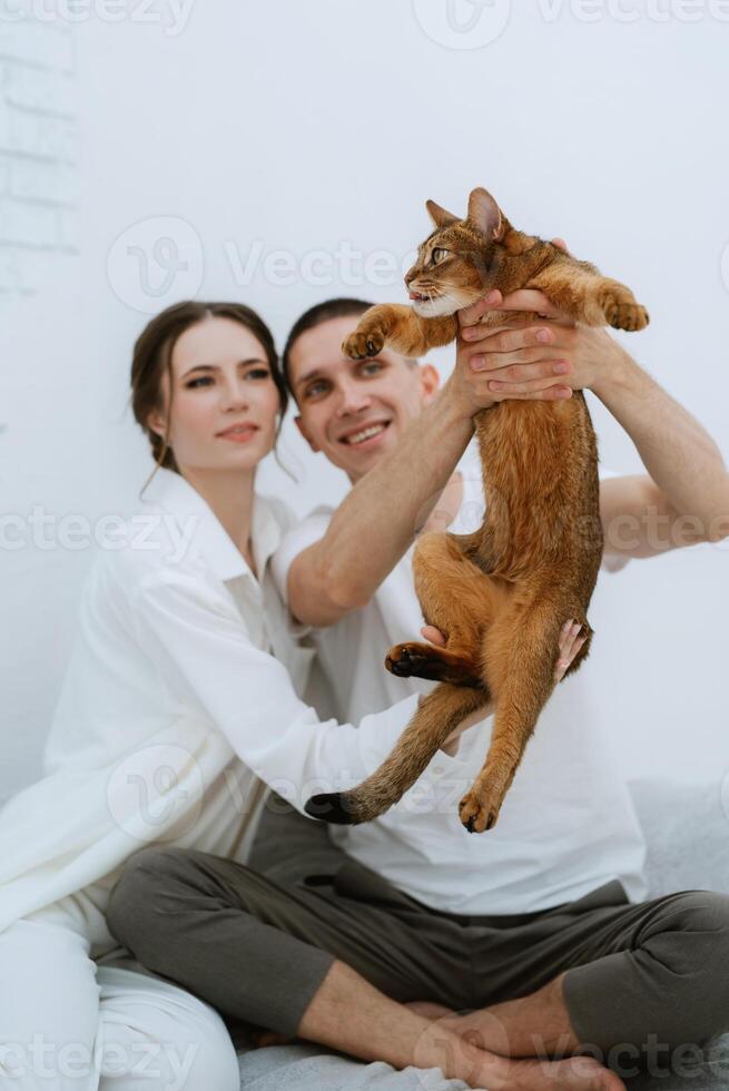 young couple guy and girl in a bright room playing with pets photo