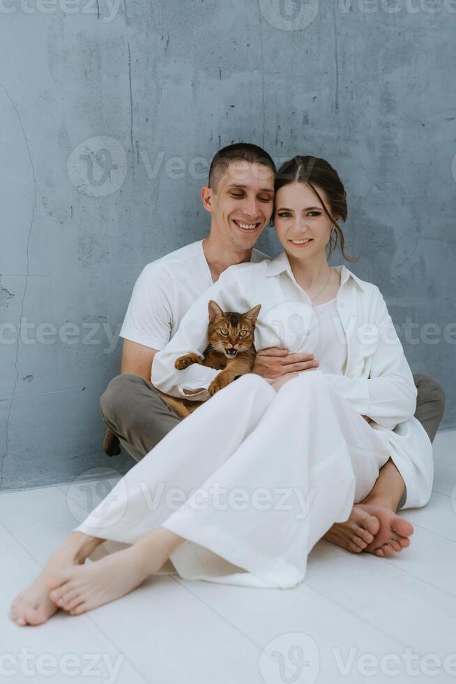 young couple guy and girl in a bright room playing with pets photo