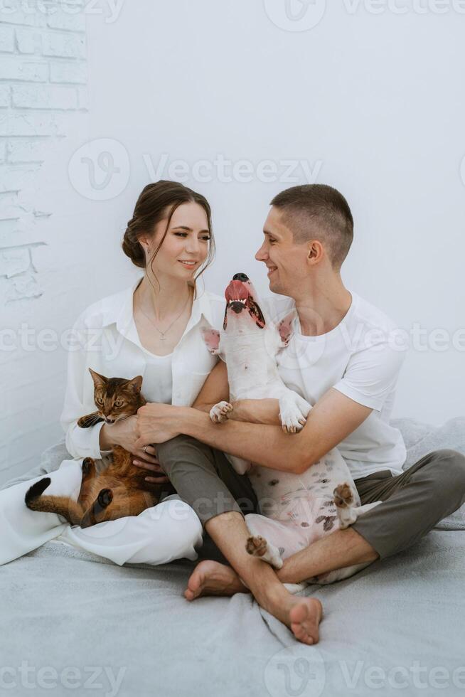 young couple guy and girl in a bright room playing with pets photo