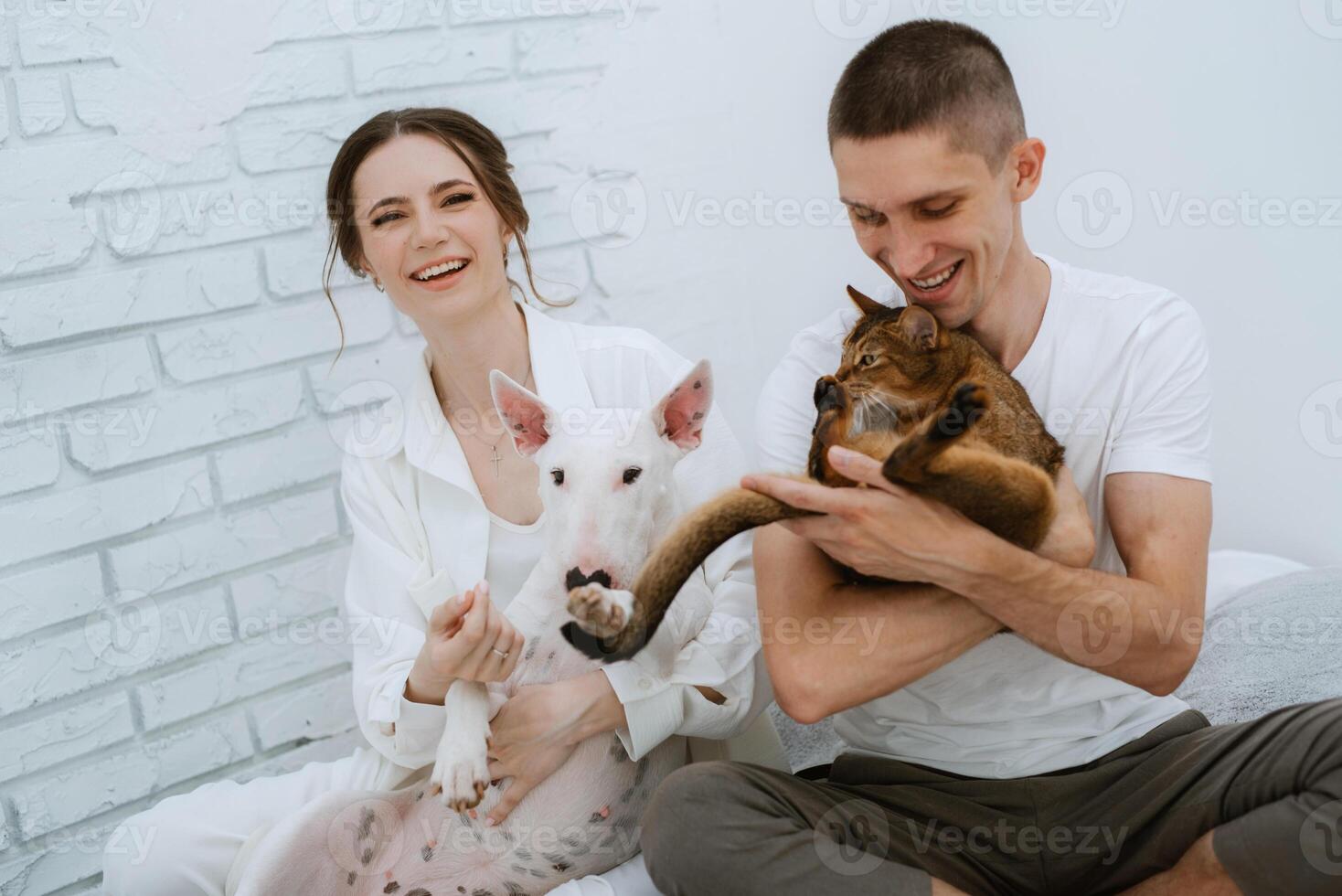 young couple guy and girl in a bright room playing with pets photo