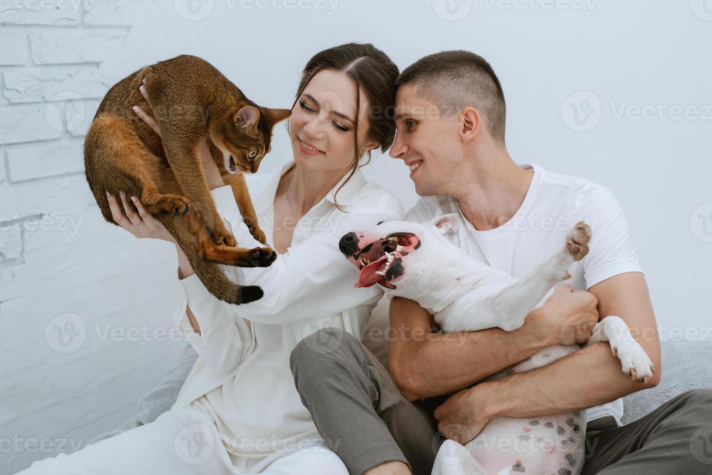 young couple guy and girl in a bright room playing with pets photo