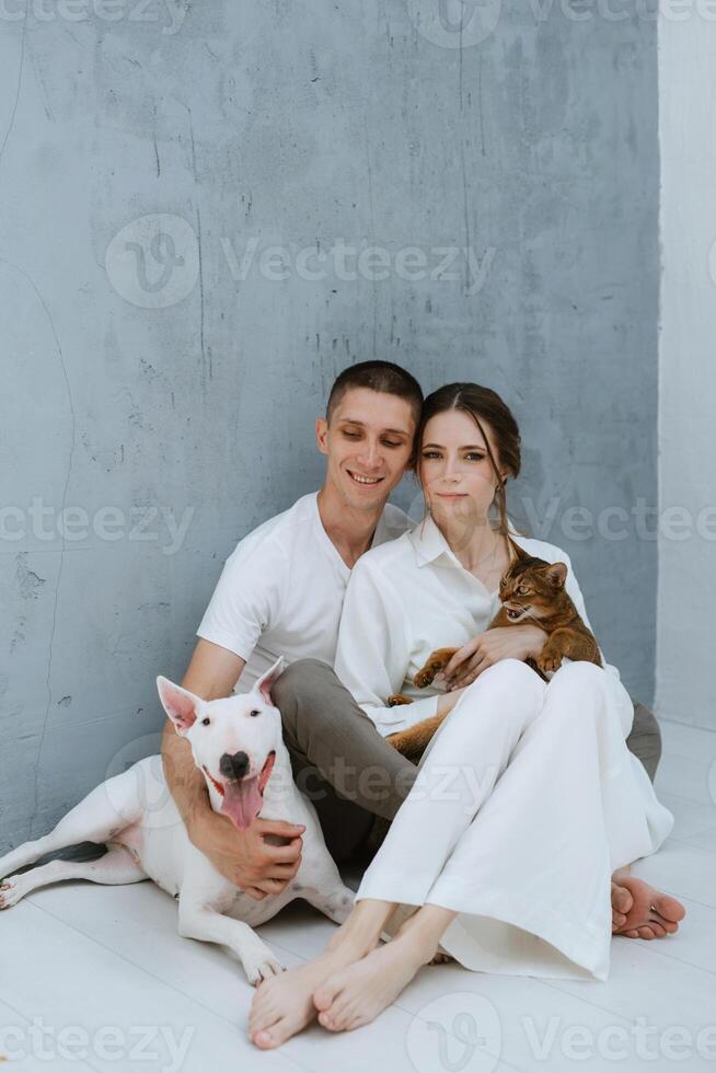 young couple guy and girl in a bright room playing with pets photo