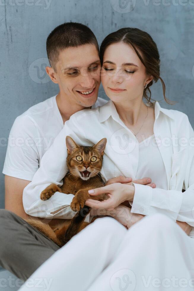 young couple guy and girl in a bright room playing with pets photo