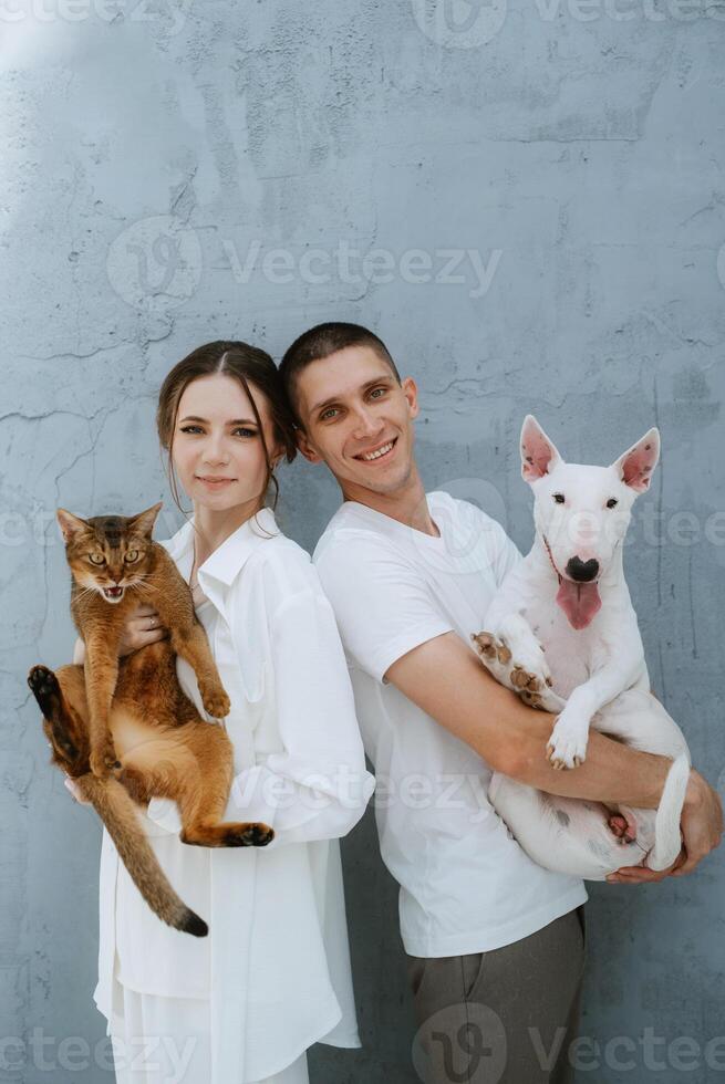 young couple guy and girl in a bright room playing with pets photo