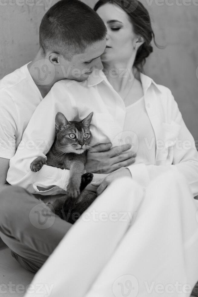 young couple guy and girl in a bright room playing with pets photo