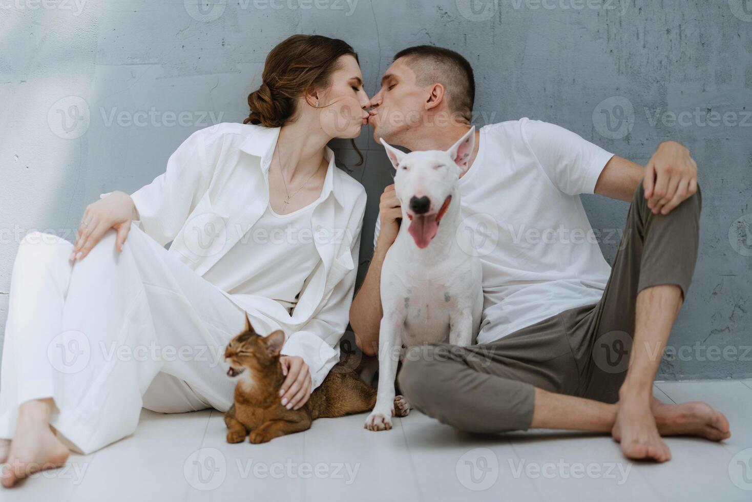 young couple guy and girl in a bright room playing with pets photo