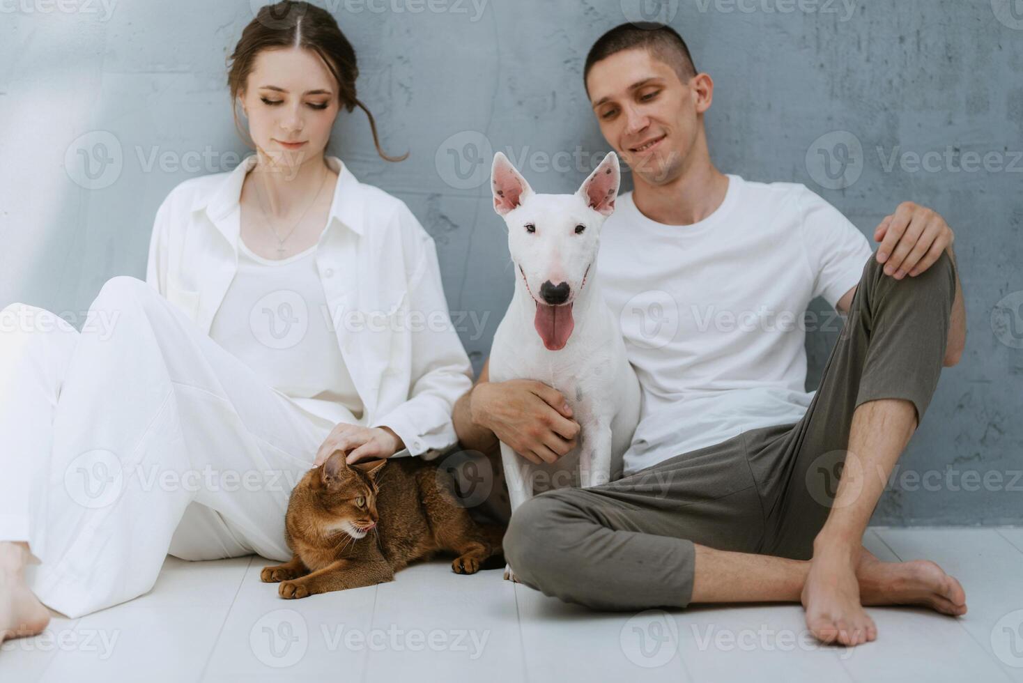young couple guy and girl in a bright room playing with pets photo