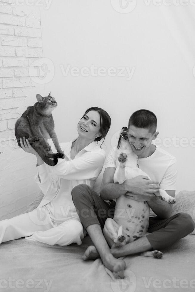 young couple guy and girl in a bright room playing with pets photo