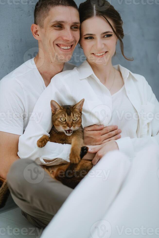 young couple guy and girl in a bright room playing with pets photo
