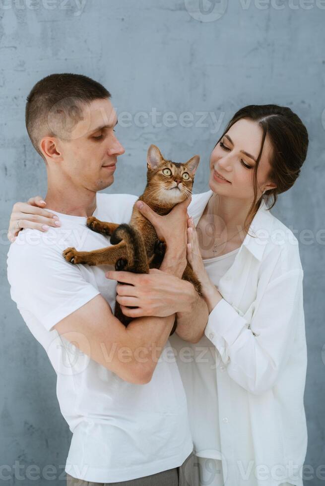 young couple guy and girl in a bright room playing with pets photo