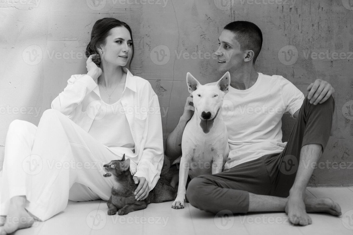 young couple guy and girl in a bright room playing with pets photo