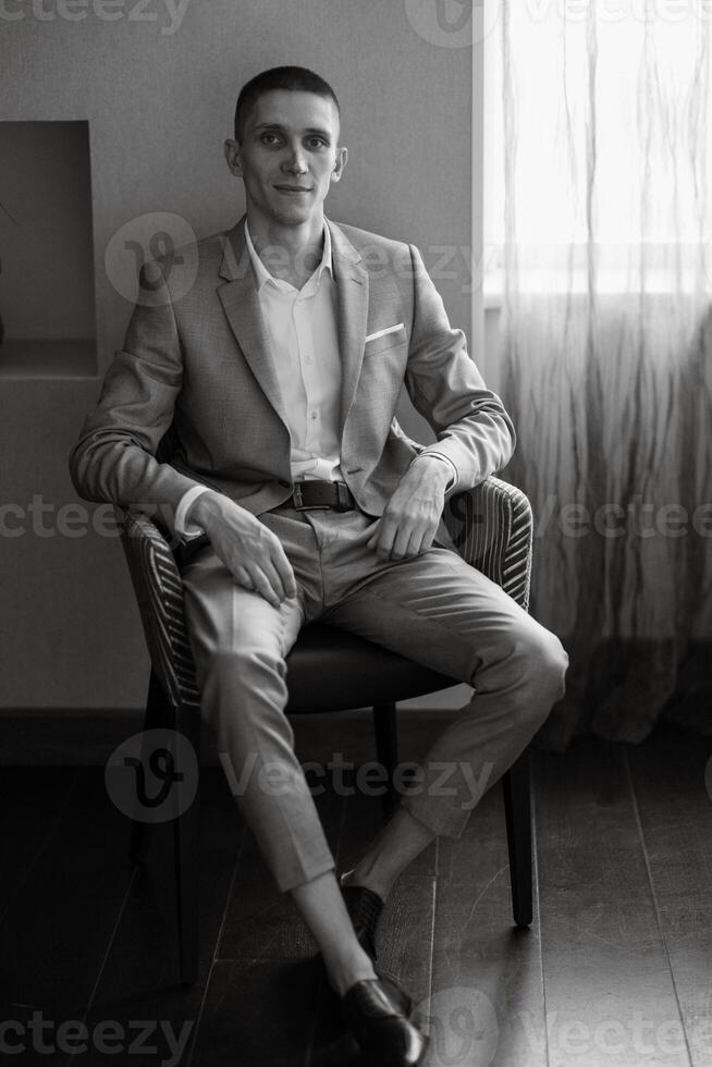 portrait of a groom in a gray plaid suit with a tie in a light bar photo