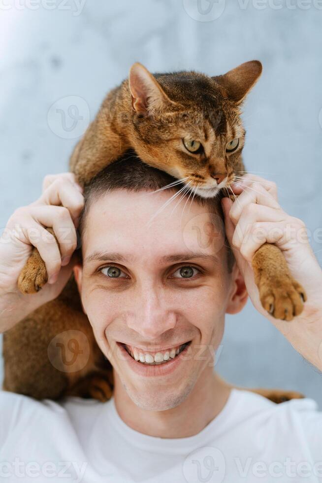 young guy in a bright room plays with a cat photo
