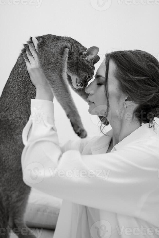 joven niña en un blanco habitación jugando con un gato foto