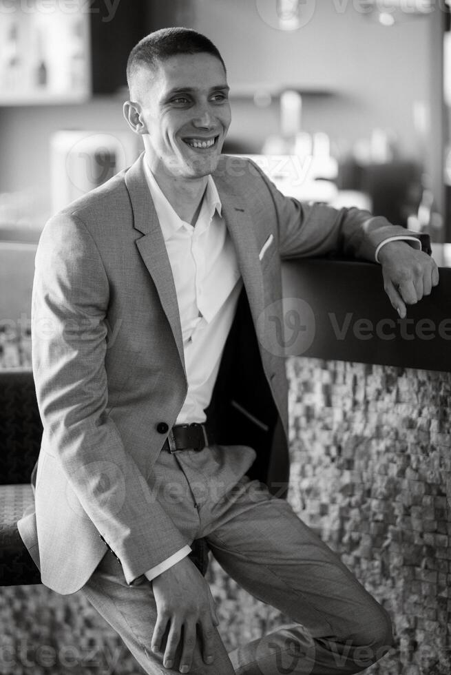 portrait of a groom in a gray plaid suit with a tie in a light bar photo