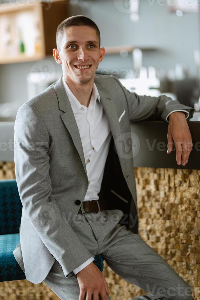 portrait of a groom in a gray plaid suit with a tie in a light bar photo