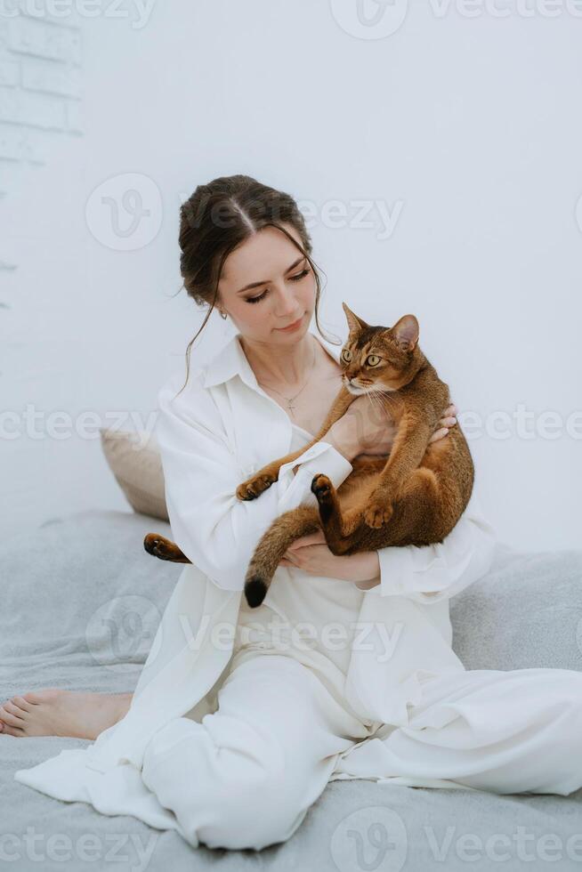 young girl in a white room playing with a cat photo