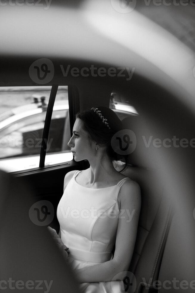 bride with a black car near a glass skyscraper photo