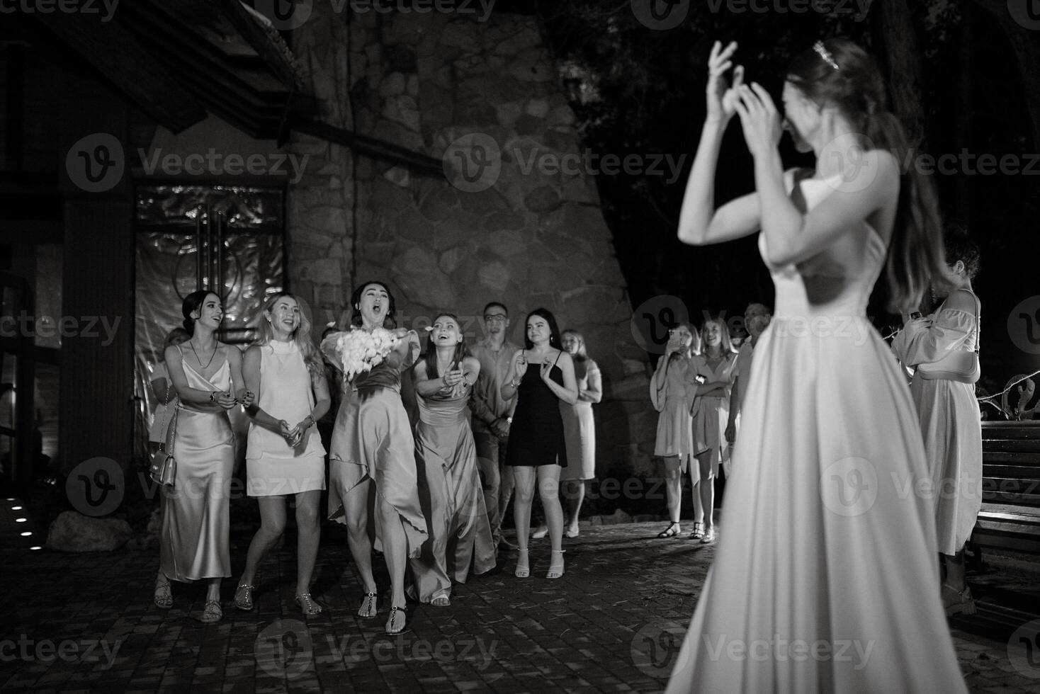 bride in a white dress throws a wedding bouquet photo