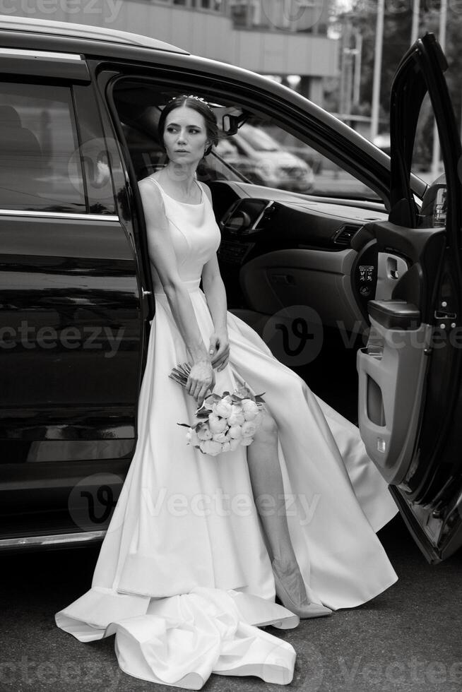 bride with a black car near a glass skyscraper photo