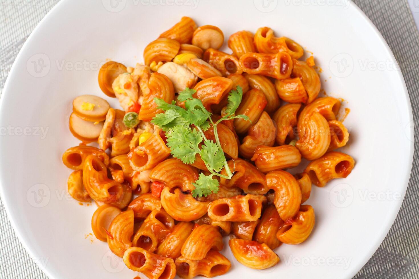 Macaroni with tomato sauce and parsley in a white bowl Served on a white plate, top view photo