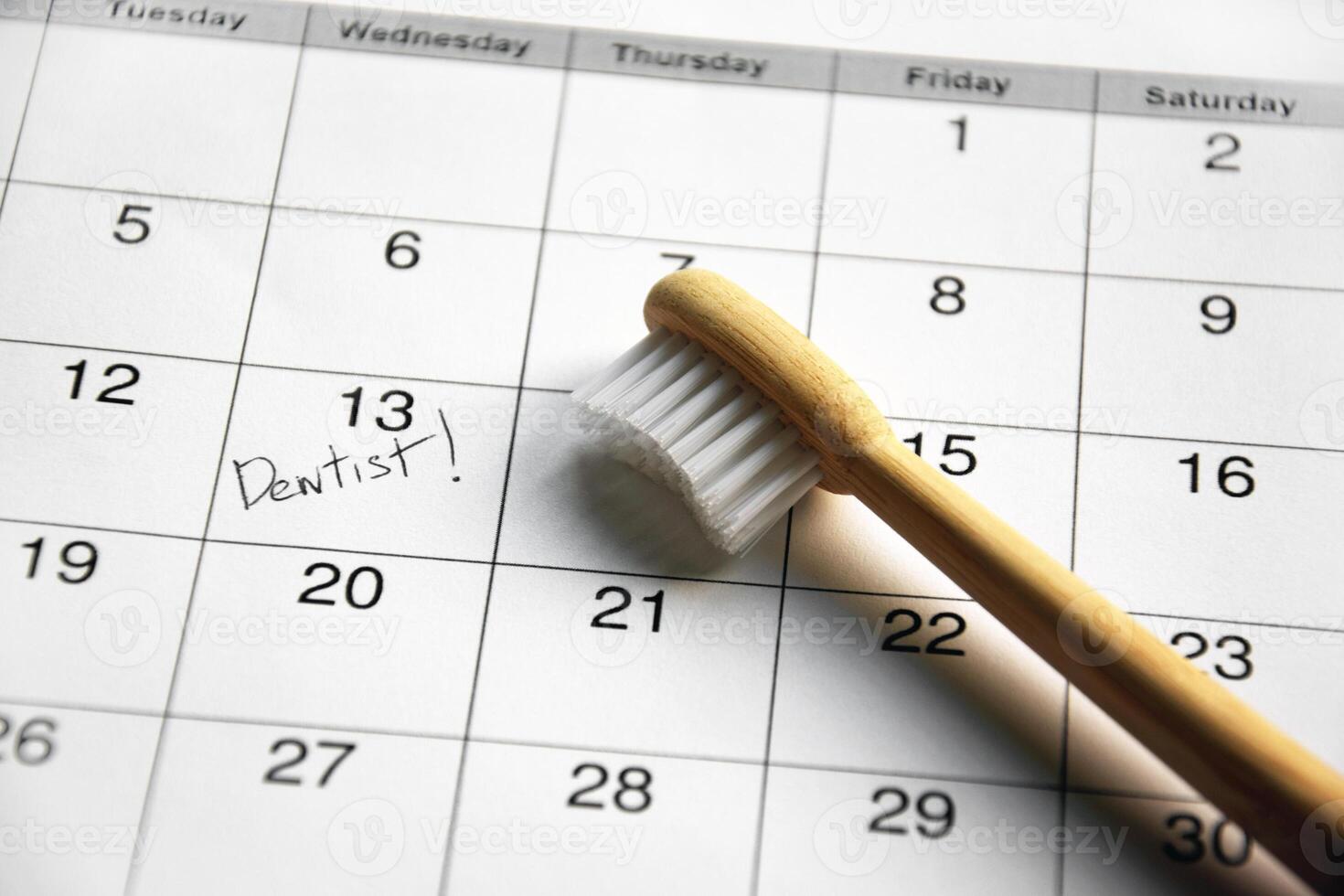 On a light gray background, there is a calendar with a dentist's note and toothbrushes. photo