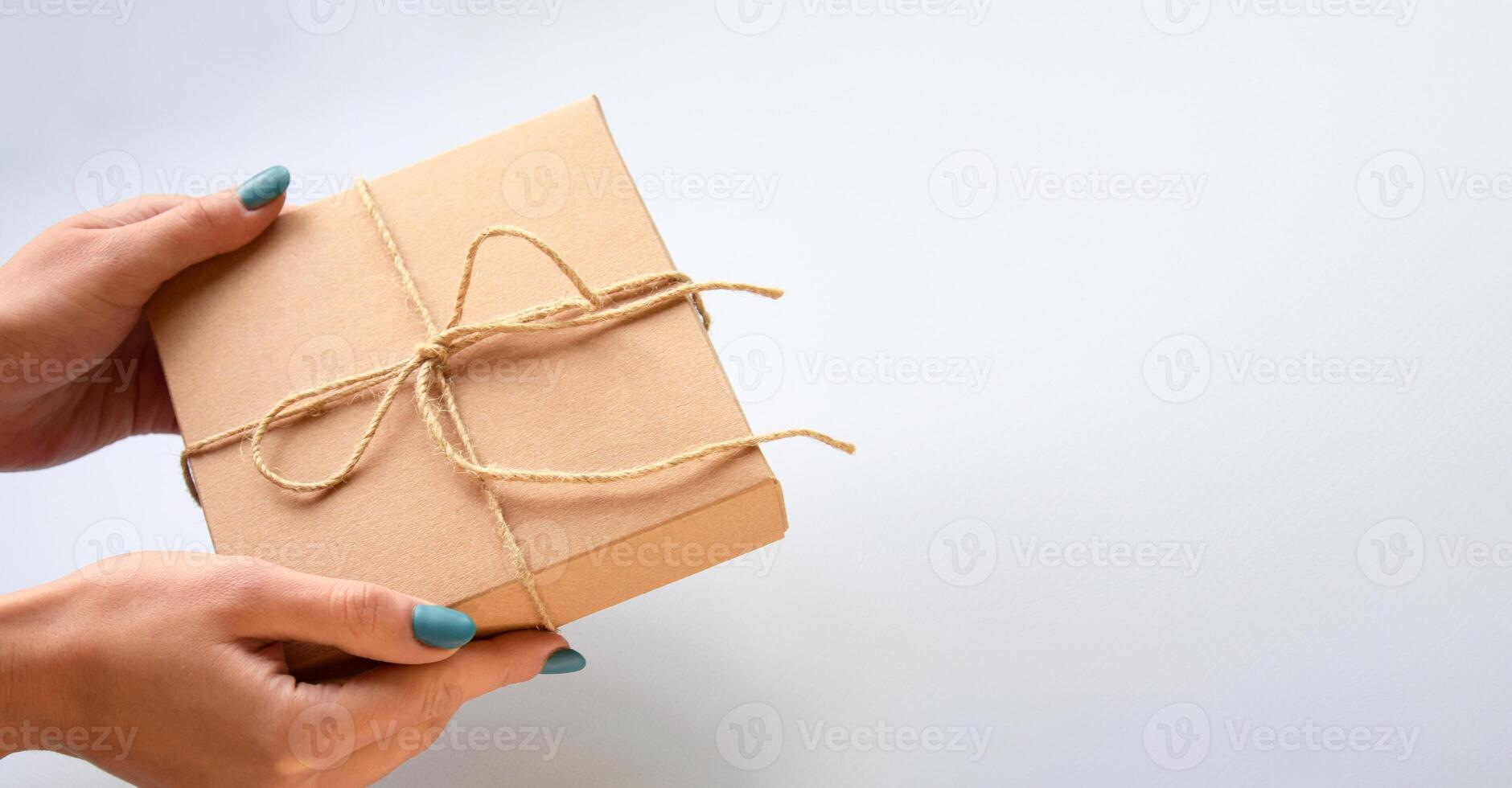 The girl holds out a craft gift box. photo