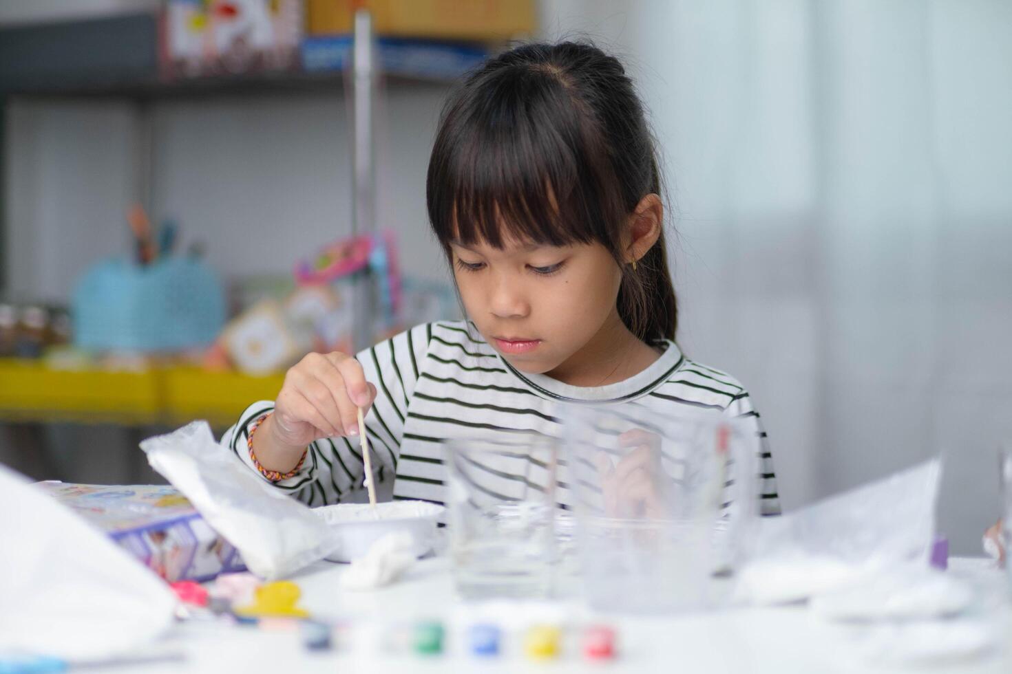 Cute little girl making DIY plaster and painting at home. Children paint on plaster sculptures with family on holiday. Imagination and creativity activities. photo