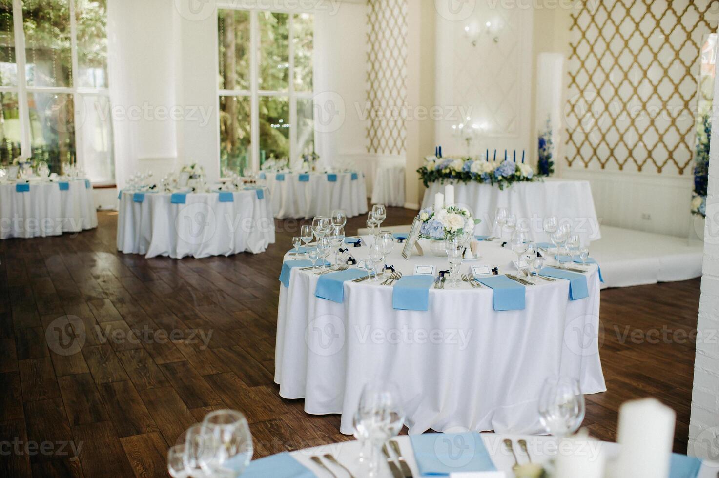 The festive table is decorated in light colors with blue napkins and flowers without food photo