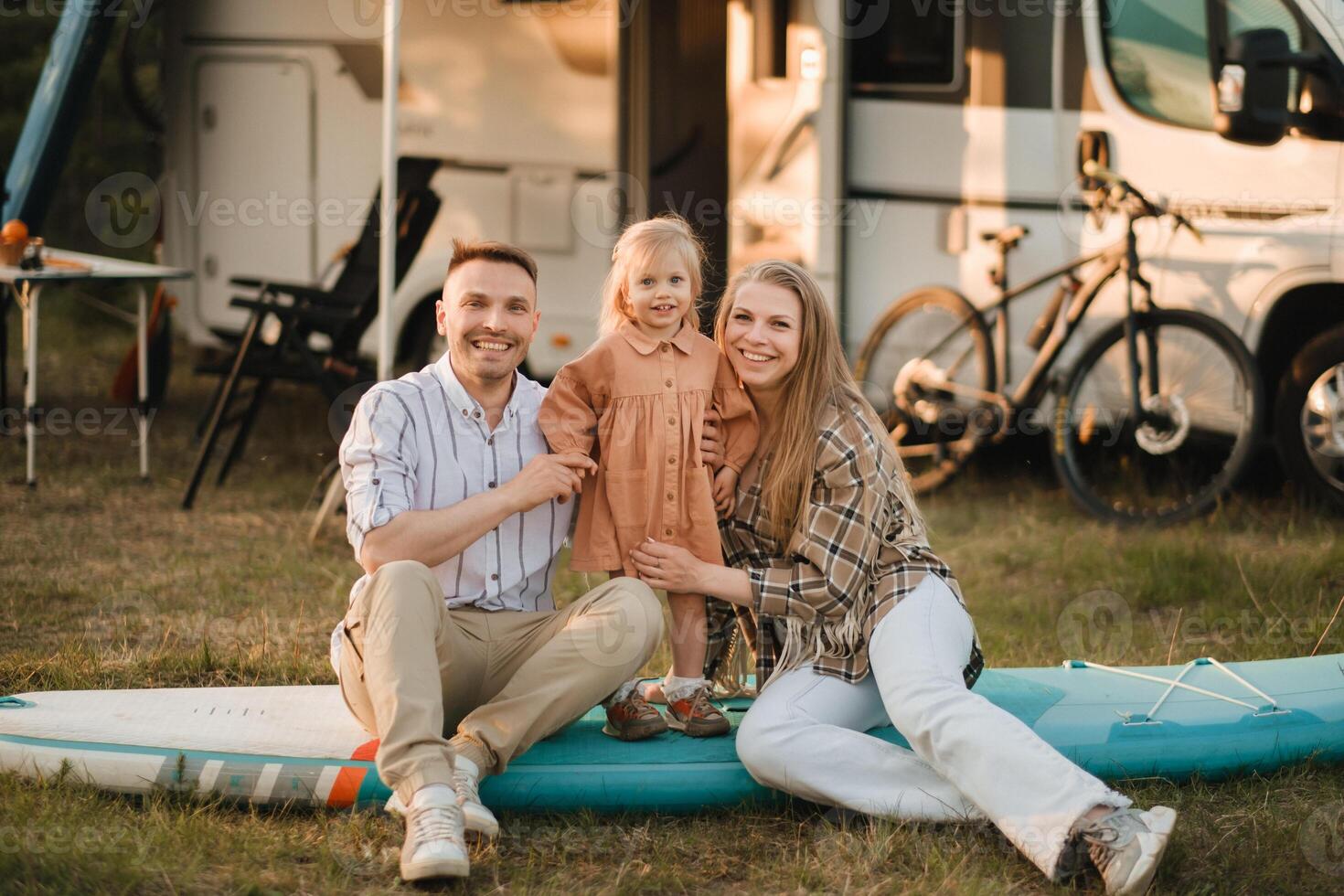 a young family is sitting on a sup board next to their mobile home photo