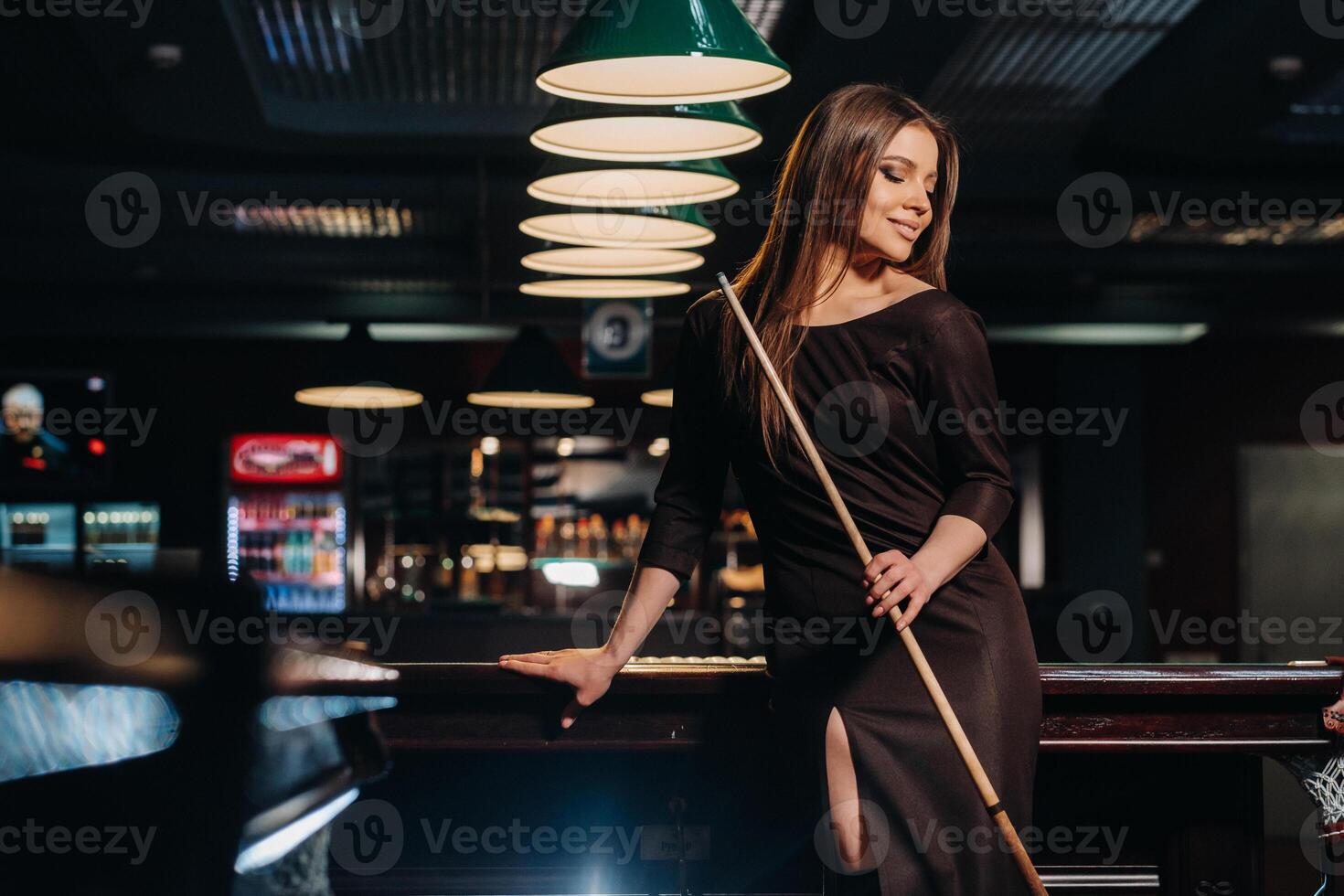 A girl in a hat in a billiard club with a cue in her hands.Pool Game photo