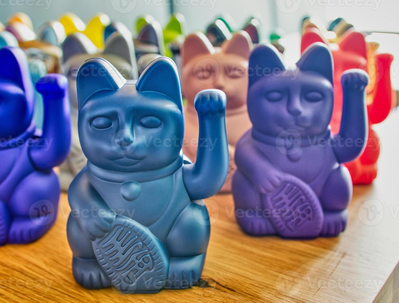 Collection of Japanese maneki cats of various colors on wooden table photo