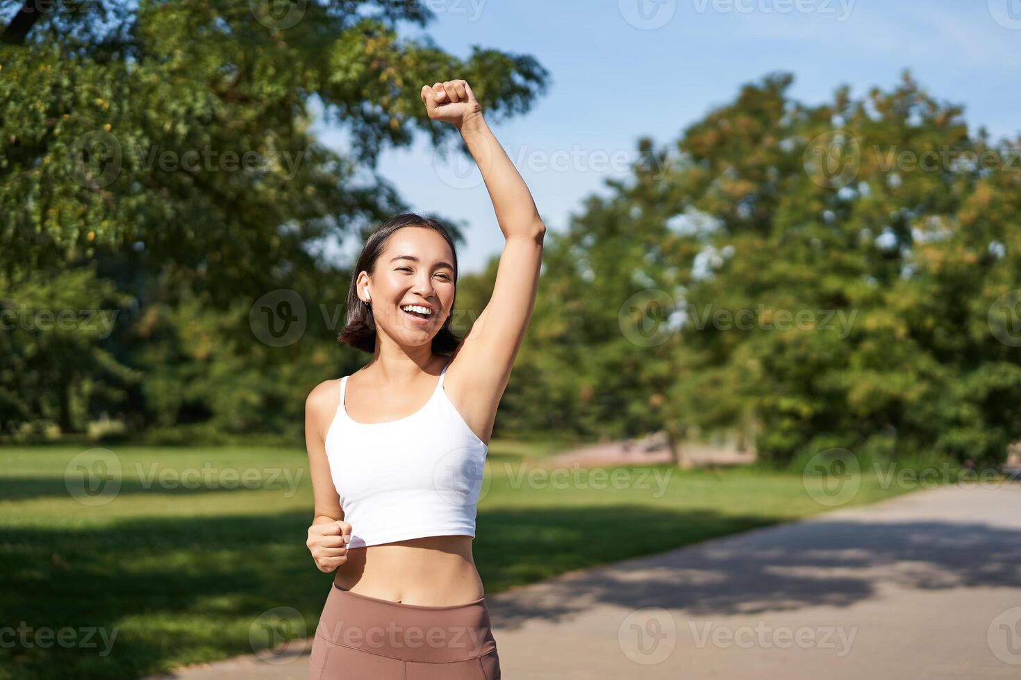 Hooray, victory. Smiling asian girl triumphing, celebrating achievement, running till finish, shouting from excitement photo