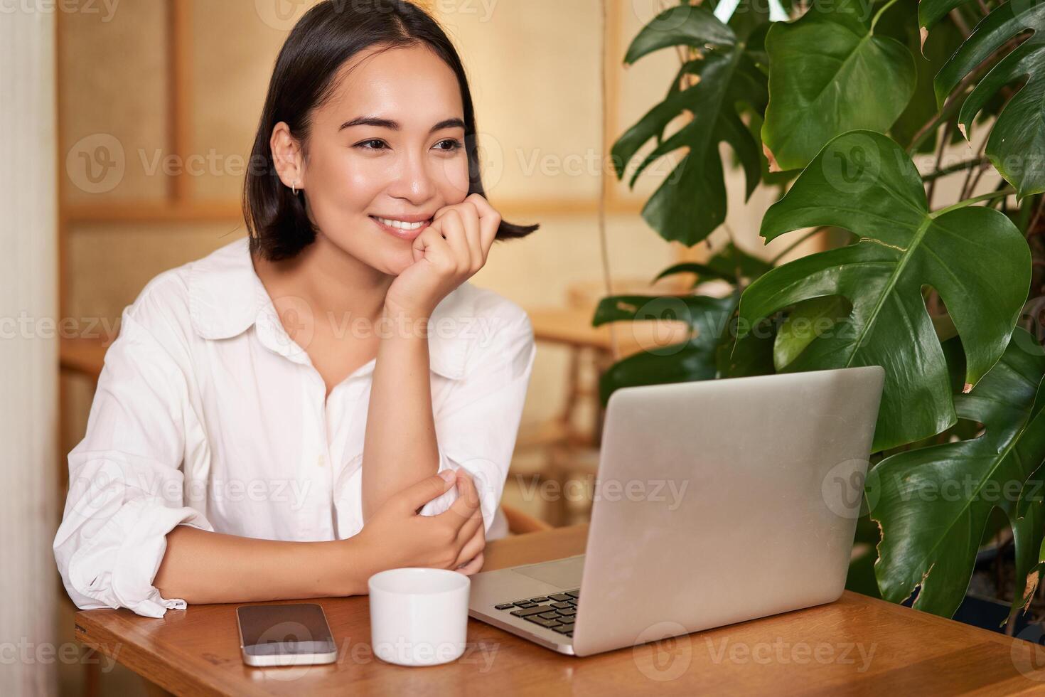 Beautiful brunette girl with laptop, sitting in cafe, working remotely, freelancing while sitting in coworking space photo