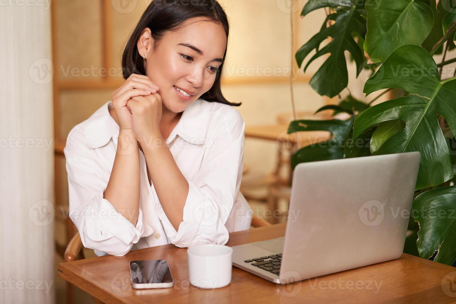 Beautiful brunette girl with laptop, sitting in cafe, working remotely, freelancing while sitting in coworking space photo